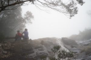 Trekkers sitting on the top of Đỗ Quyên Waterfall in a rainy day