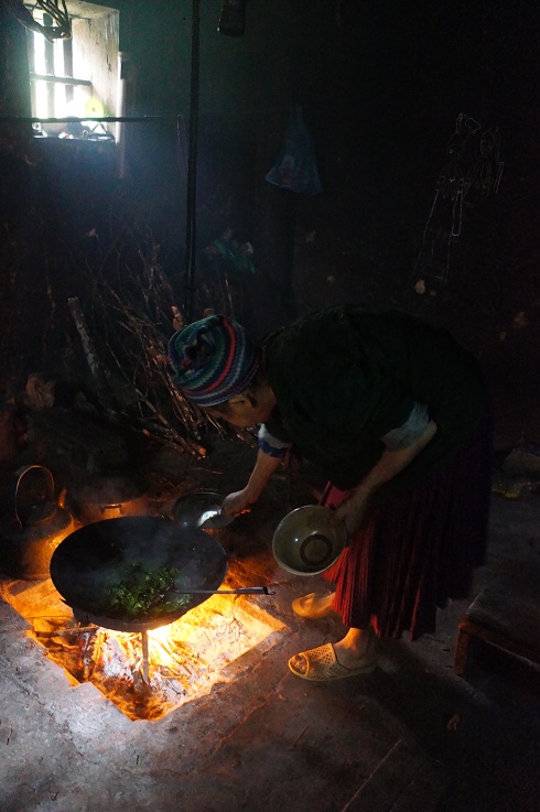 Mrs. Va stir-frying mustard leaves on the open fire