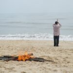 A pile of fire and a man on the beach