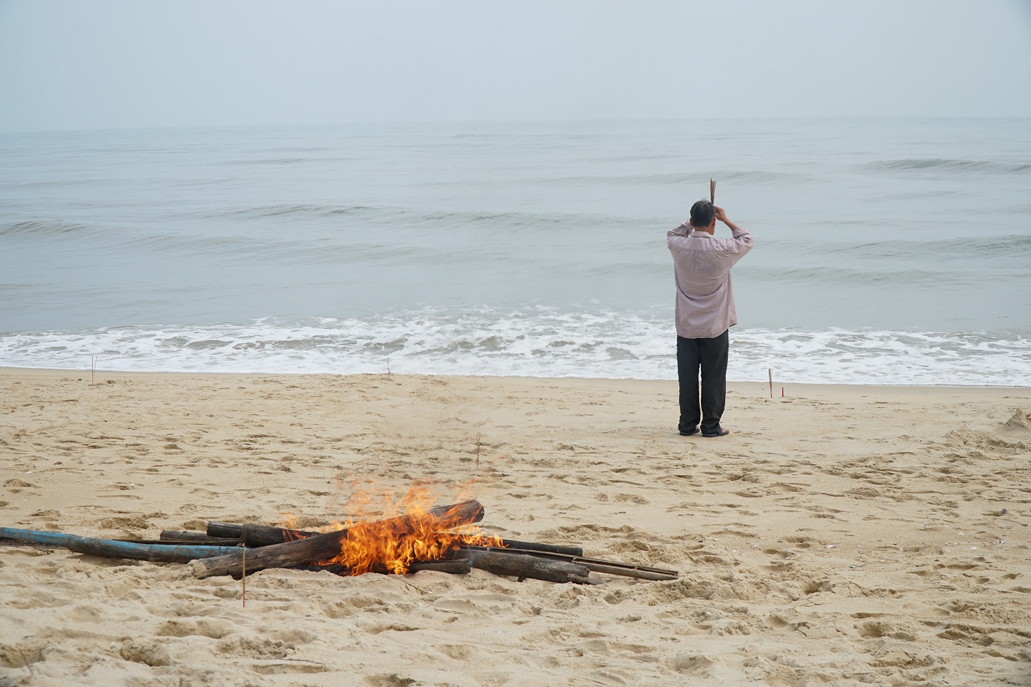 A pile of fire and a man on the beach